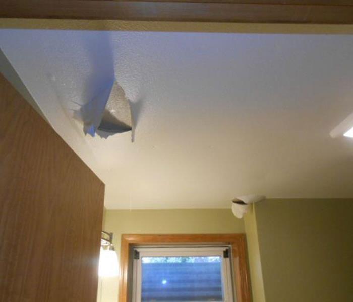 White ceiling bubbling with water in a room