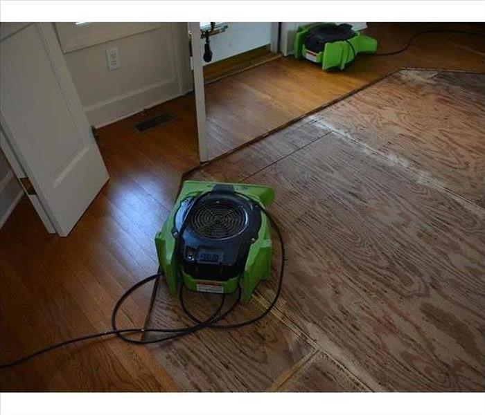 hardwood flooring removed from a portion of the floor with a green fan setup