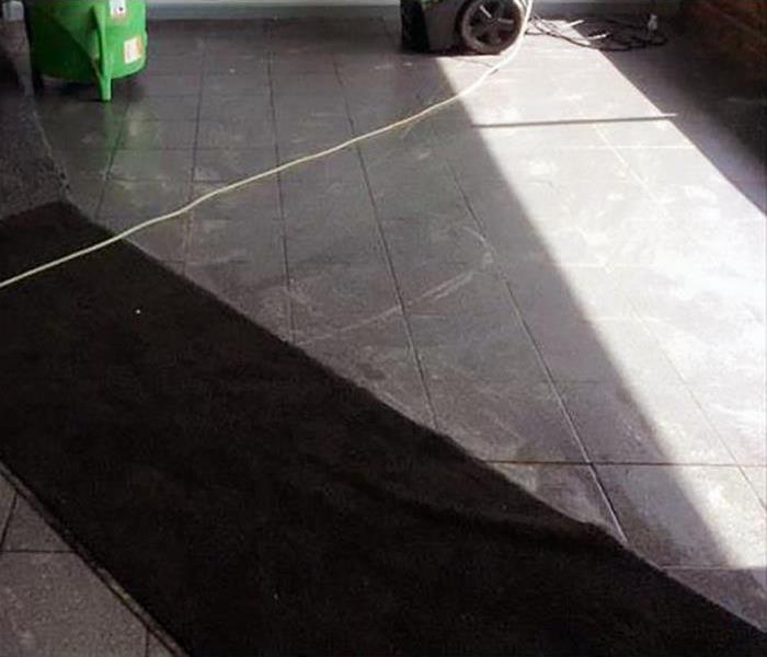 black tile floor with green SERVPRO equipment in the distance