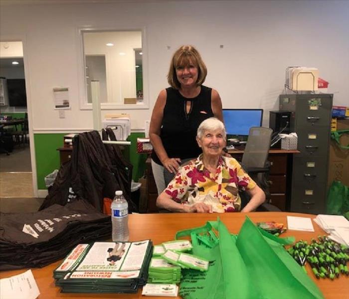 Two females in a office with SERVPRO bags and pens