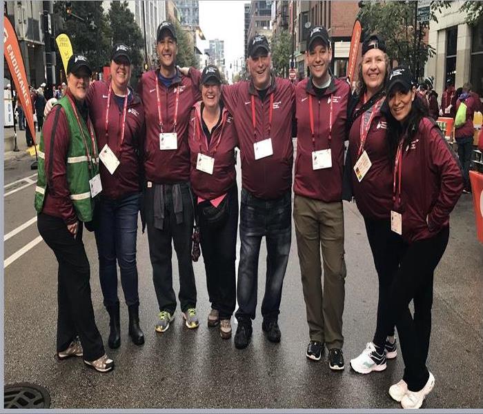 A group of people standing on a street wearing maroon jackets.
