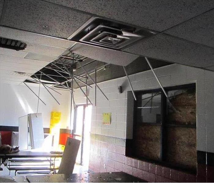 A classroom with a ceiling that has fallen through with water dripping down
