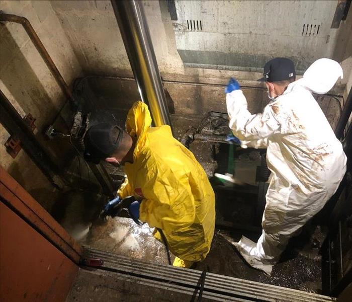 SERVPRO technicians in a wet elevator shaft with cleaning tools