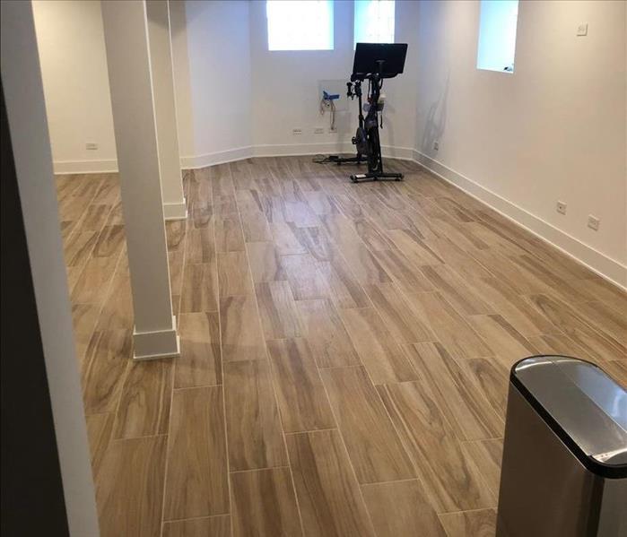 A clean, dry room with white walls, wood flooring, and an exercise bike in the corner