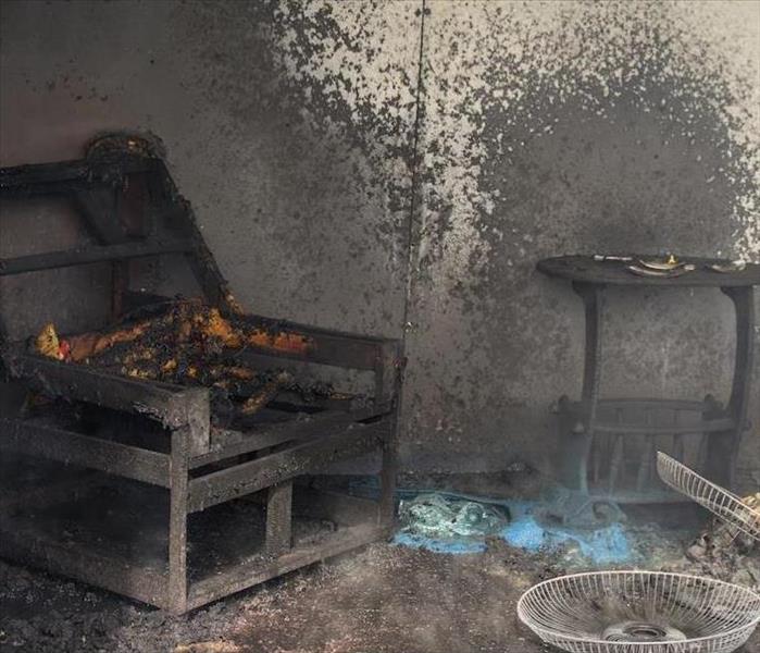 room with burned chair and walls covered in soot damage
