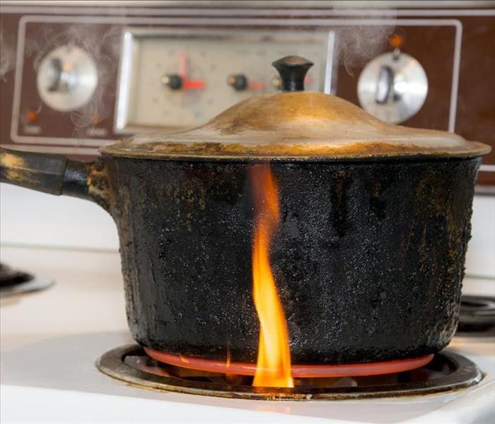 pot on a stove with a flame rising up