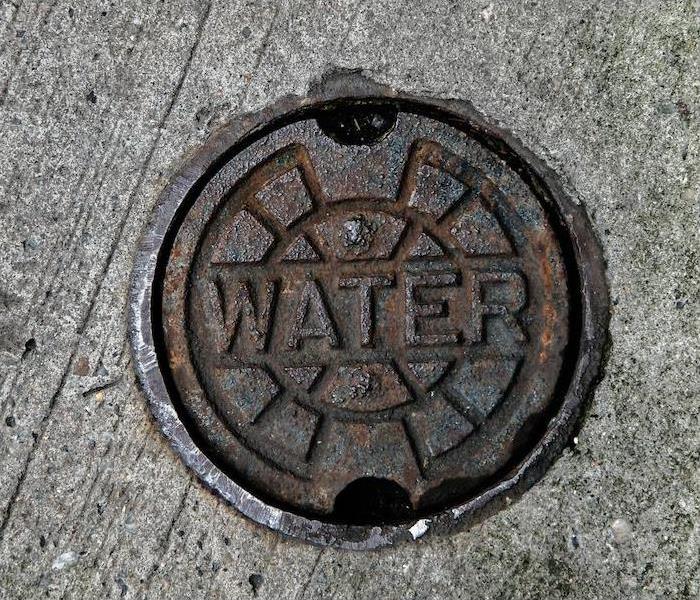  img src =”water” alt = " a picture of a manhole cover that says 'WATER' on the pavement ” >