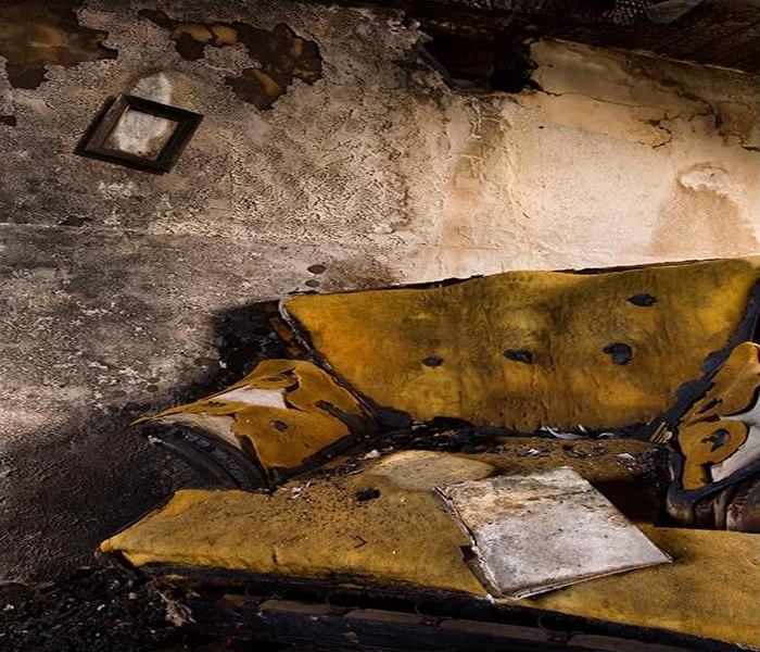 living room with yellow couch and walls burned and covered in soot damage