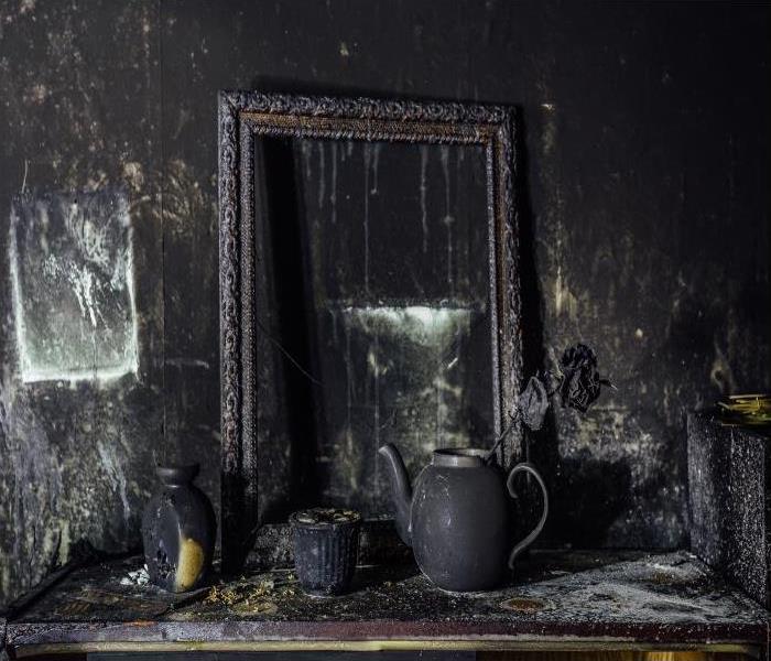 table with decorations and a mirror burned and covered in soot damage