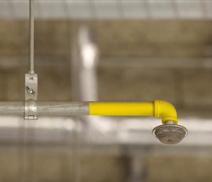 A yellow fire sprinkler hanging down from a ceiling
